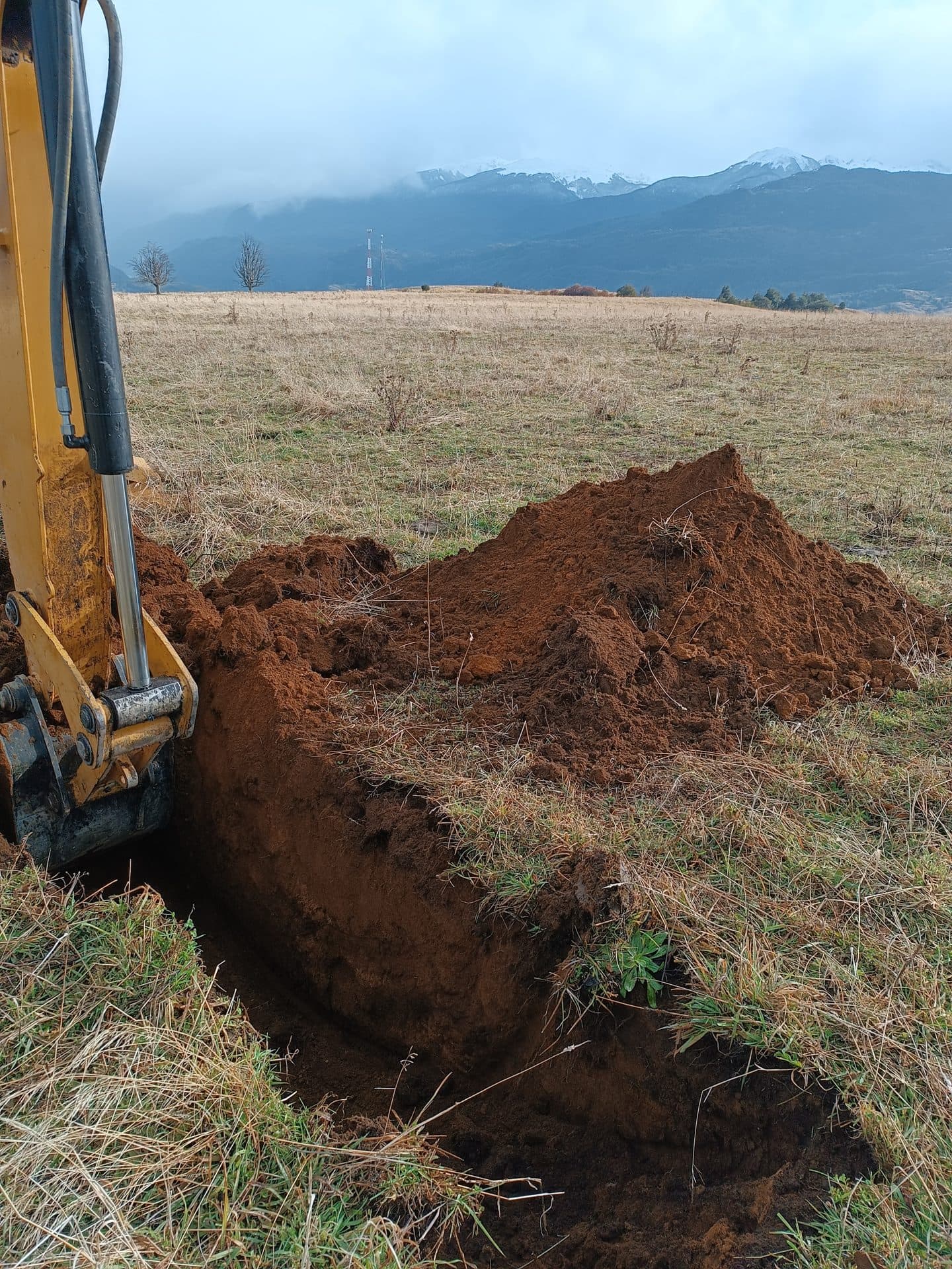 Zanja de calicata abierta en la estepa patagónica, con la cordillera al fondo.