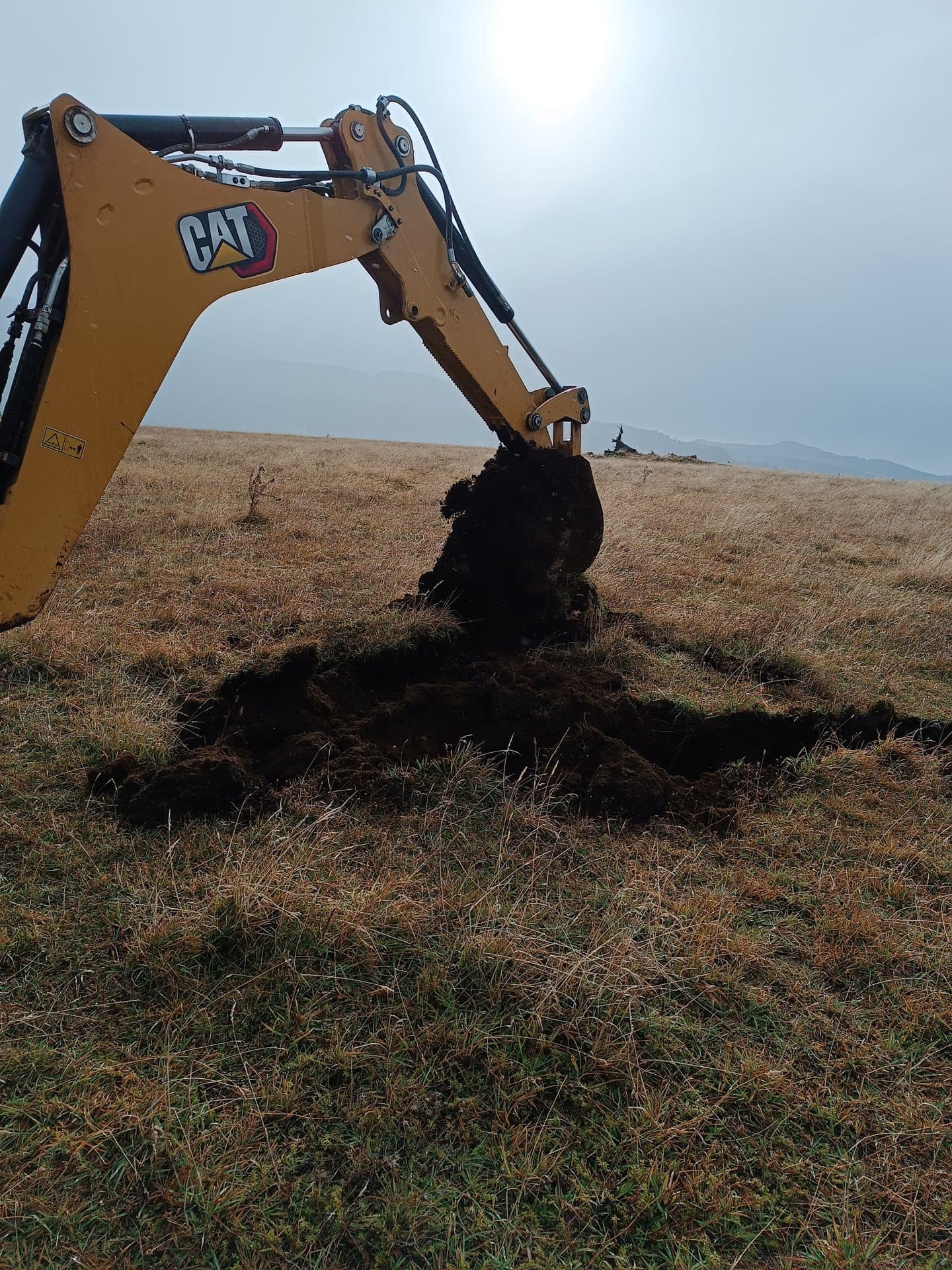 Retroexcavadora abriendo una calicata durante un monitoreo de terreno.