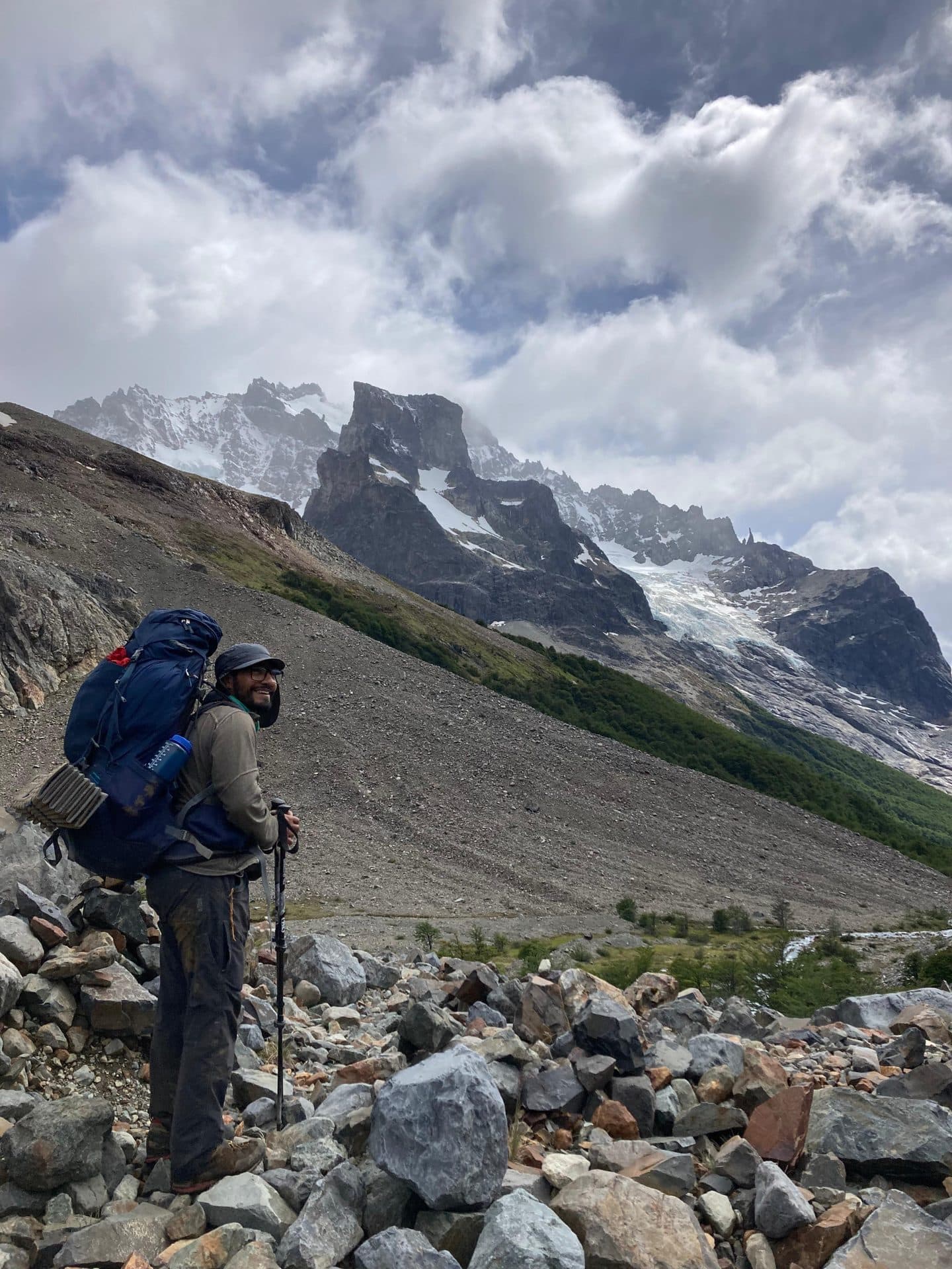 Geólogo con mochila de terreno frente a un glaciar y agujas graníticas de la Patagonia.